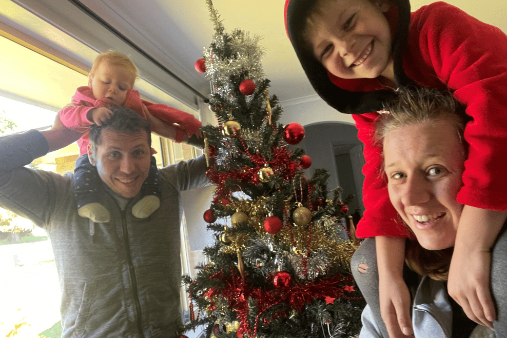 Anastasia and family, laughing around Christmas tree
